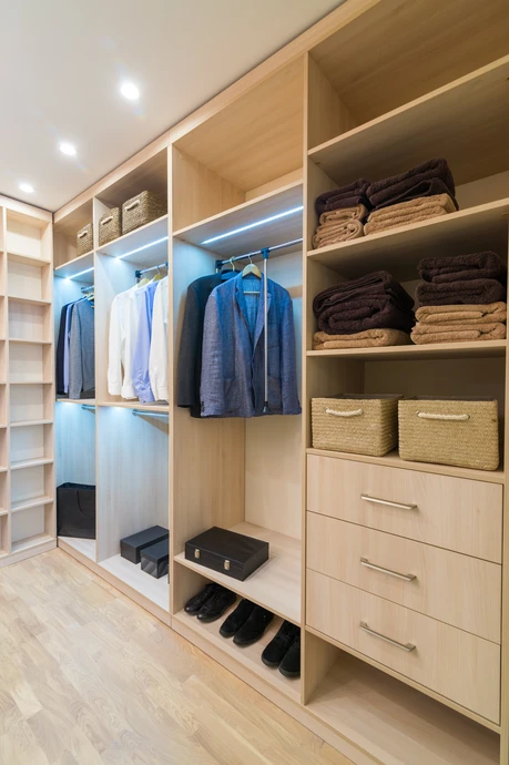 Menuisier en atelier utilisant une défonceuse pour façonner les contours et détails d'un panneau de medium posé sur un établi, concentré sur son ouvrage, poussière de bois visible, matériel professionnel de menuiserie en arrière-plan.
