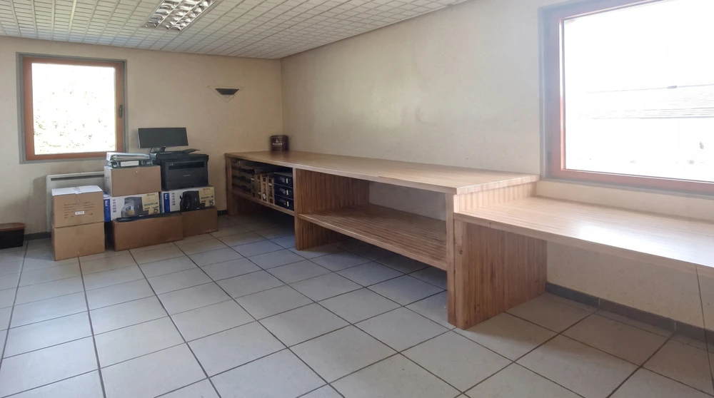 Bureau vide en cours de déménagement, comptoir long en bois clair style guichet, étagères intégrées